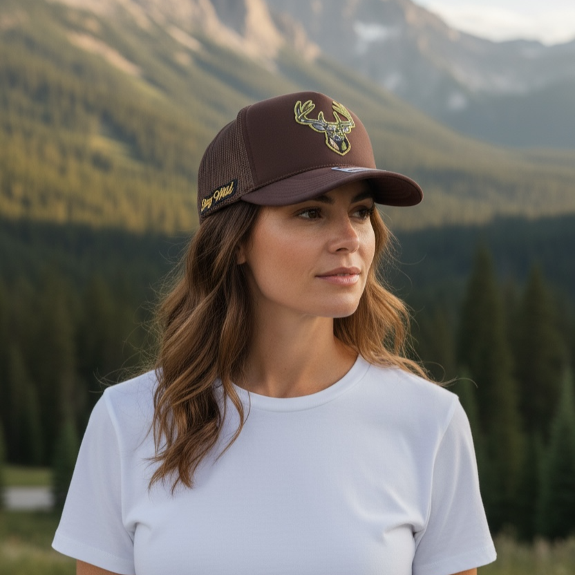 Woman wearing a brown cap with a logo in a mountainous landscape